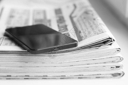 报纸和智能手机小报期刊和手机经营理念新闻杂志折叠堆放成堆背景图片