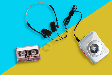 带有收音机和盒式磁带的便携式磁带播放器以及黄色和蓝色背景上的耳机图片