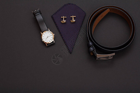 手表配有黑色皮革表带袖扣的手帕和黑色背景上带金属扣的皮带男士图片