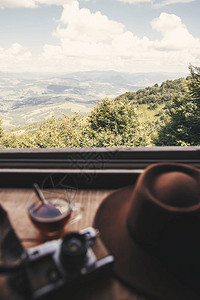 热茶在玻璃杯和时髦帽子的背景下的树林和山脉的美丽景观图片