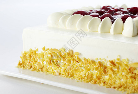 甜美味的蛋糕装饰着白奶油和樱桃在白图片