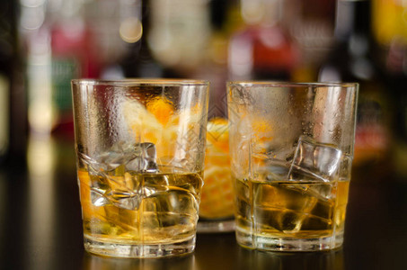 一杯威士忌加冰块和咸点心在瓶子和酒吧的背景高清图片
