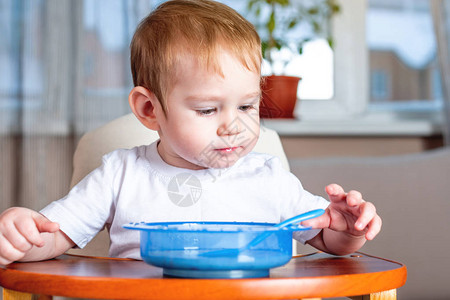 小男孩在的儿童餐桌旁用勺子自己吃饭健康婴图片