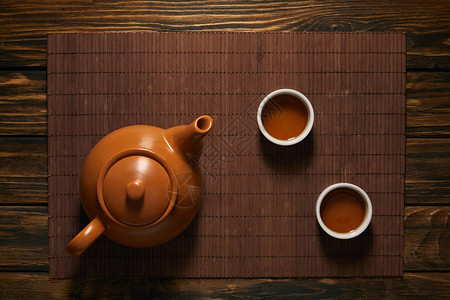 竹席上棕色陶瓷茶壶和茶杯的俯视图图片