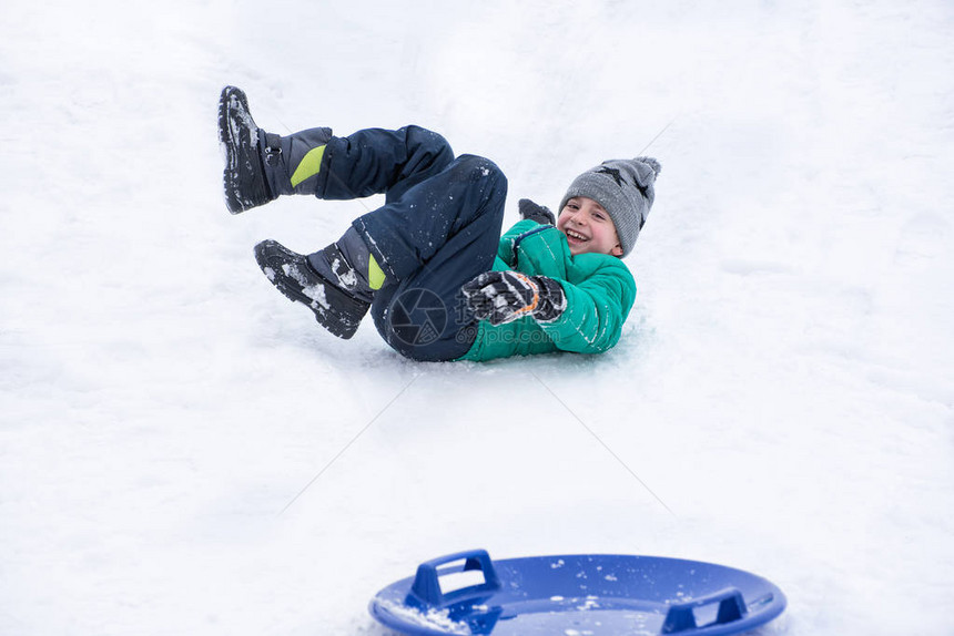 男孩骑着雪碟滚下山坡冬季运动会图片