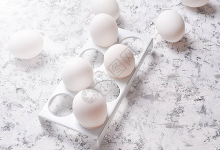 白色混凝土背景上带白鸡蛋的塑料托盘图片