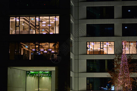 晚上办公大楼深夜工作玻璃窗帘墙办公室大楼蓝色灯光照亮楼顶图片