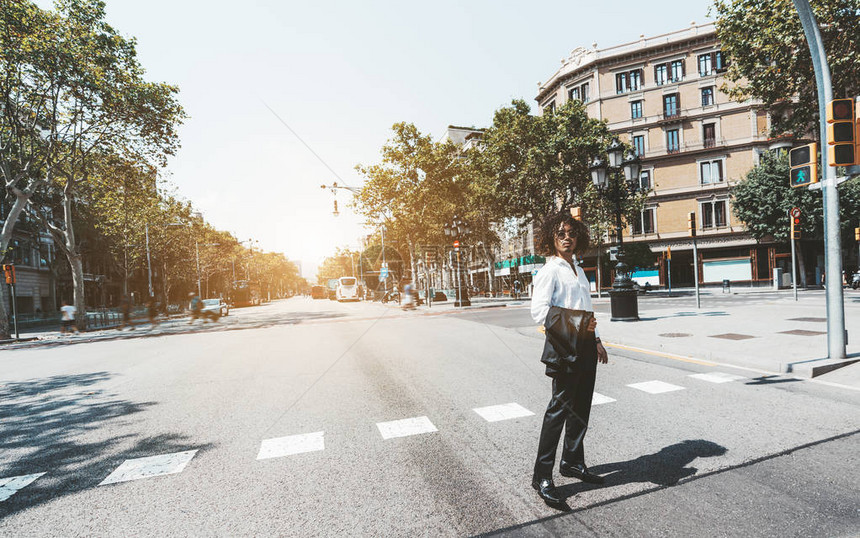 一位年轻英俊的商人正在使用人行横道穿过欧洲城市的街道图片