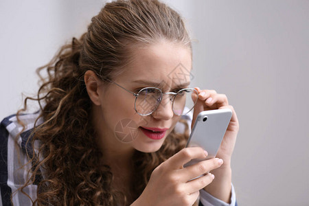 视力不好的女人试图在手机屏图片