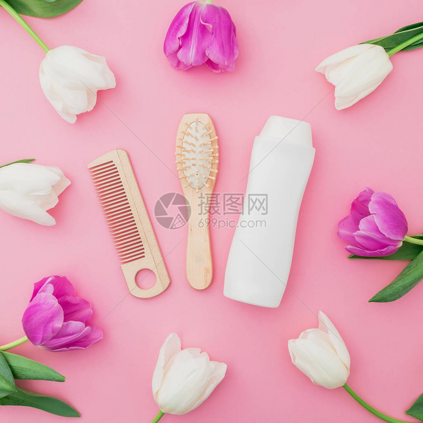以香波梳子和郁金花在粉红背景上的发型概念美容成分平面图片
