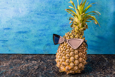 蓝色背景的黑墨镜上的菠萝里普热带休息的概念背景图片