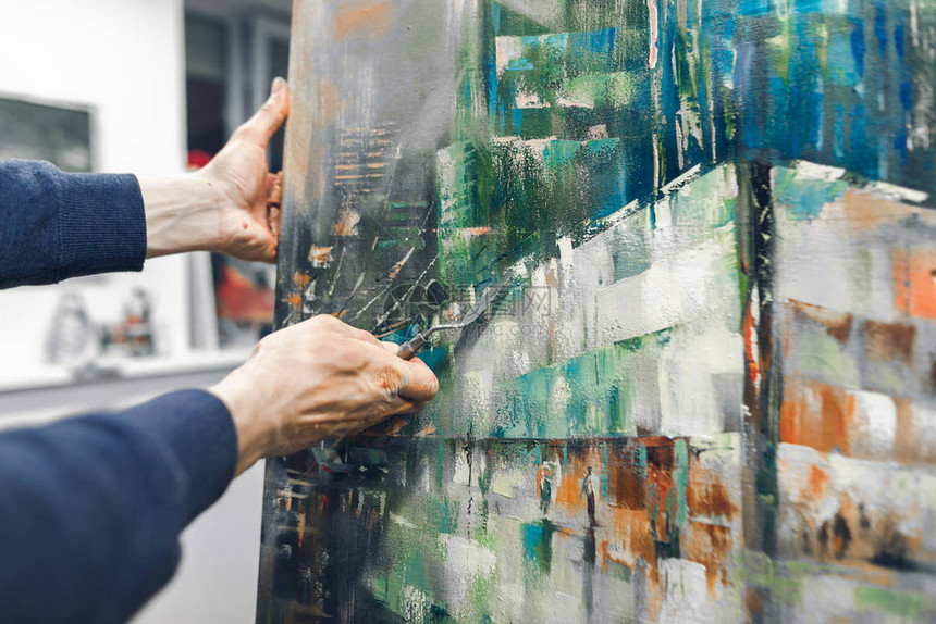 艺术家手里拿着刀调色板画一幅画艺术家的手用刀调色板在画布上绘画和放置的地方创作如画的作绘画概图片