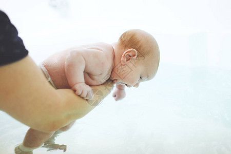 母亲的手在水中给两个月大的婴儿洗澡儿童的健康硬化和积图片