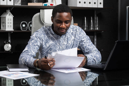 成功的年轻非洲领导人坐在办公室的办公桌前图片