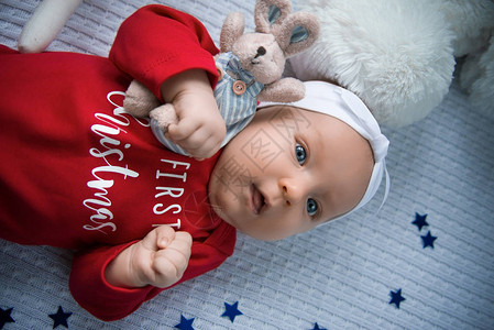可爱的新生婴儿躺在一个小床上穿着红色服图片