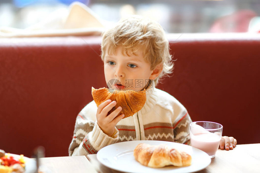 可爱的健康男孩在咖啡馆里吃羊角面包和喝草莓奶昔快乐的孩子与父母或在托儿所吃早餐蔬菜鸡蛋作为儿