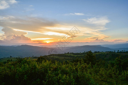 山丘上黄色和蓝色的天空与山地风景的田野日落美景背图片