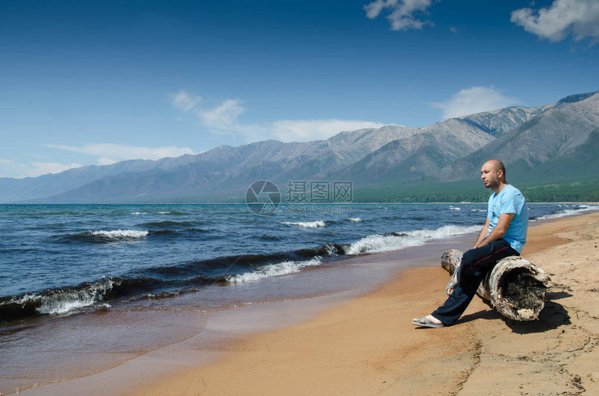 男人们坐在俄罗斯巴古津湾Baikal湖附近海滩上一个非常古老的木质腐图片