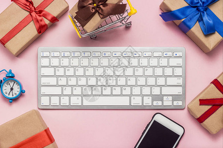 键盘闹钟手机和礼品盒在粉红色背景的键盘周围布置图片