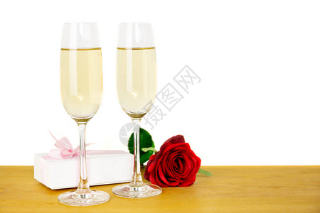 带玫瑰花和情人节礼物盒的香槟杯子图片
