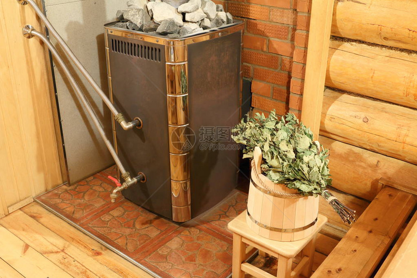 俄罗斯浴场内部俄罗斯浴室的蒸汽浴室里有一个带桦木扫帚的桶一个木炉和图片