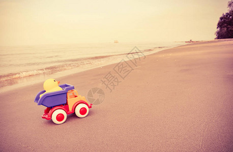 沙滩上的黄鸭玩具和彩色汽车儿童假期快乐儿童沙滩彩色玩具图片