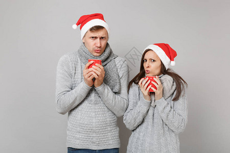穿着红色圣诞帽灰色毛衣围巾有趣的情侣女孩拿着茶杯图片