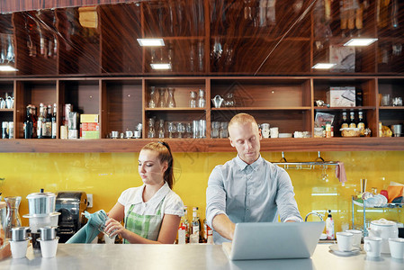 在咖啡店老板用笔记本电脑与咖啡店老板在柜台做酒吧招图片