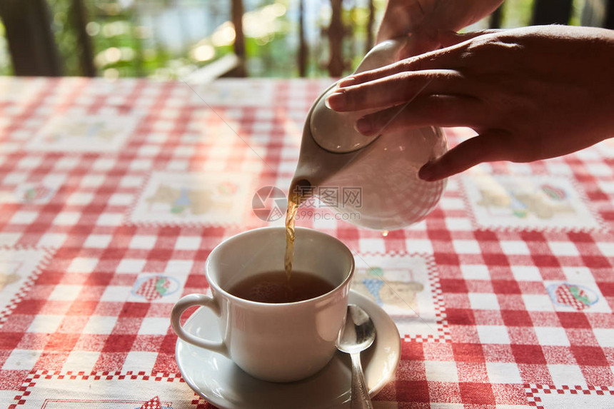 女孩把茶倒在杯子里桌上的一杯茶一杯现泡红茶图片