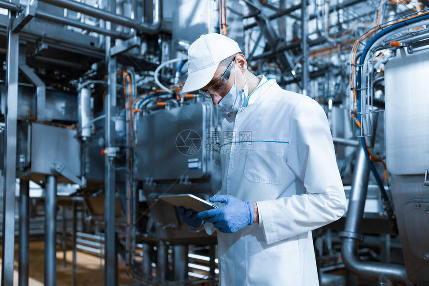 集中的技术人员站在乳制品厂的生产部门图片