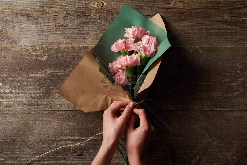 将粉红康兰花包装在木制表面的手工纸图片