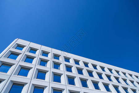 现代建筑背景蓝色天空上由混凝土和玻璃制成的白色建筑的图片
