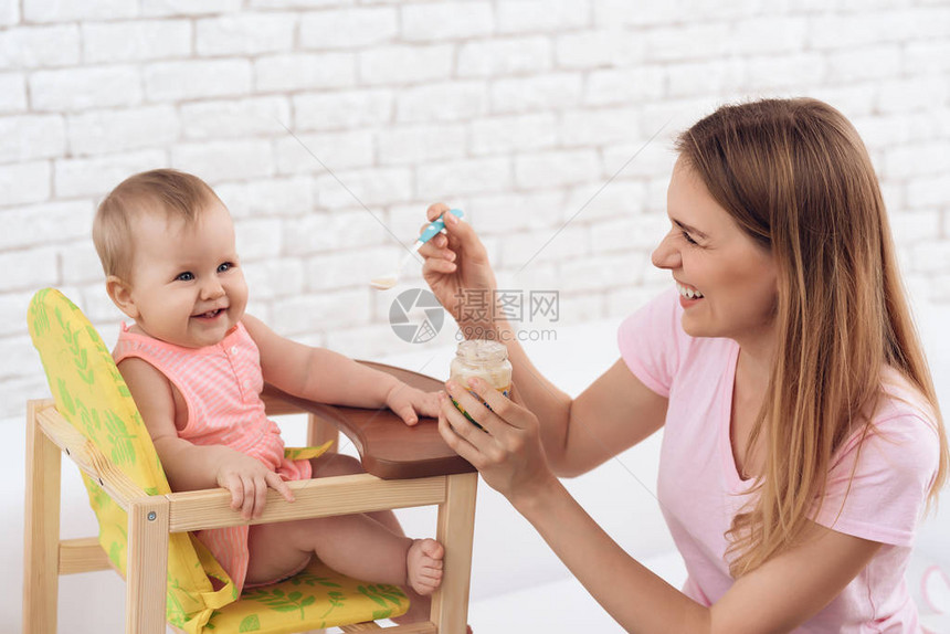 微笑的母亲带着果泥喂养微笑的婴儿家图片