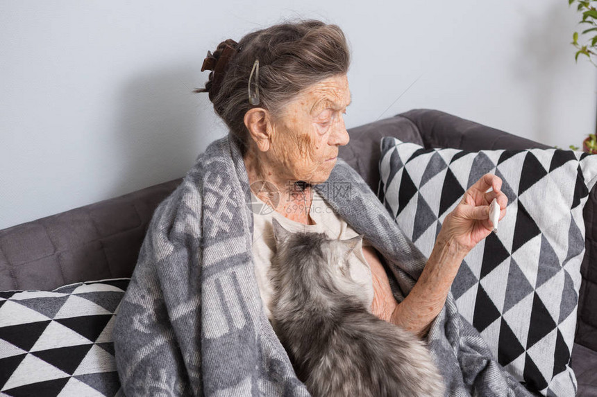 一位白发苍皱纹深邃的高加索老奶正坐在家里的沙发上图片