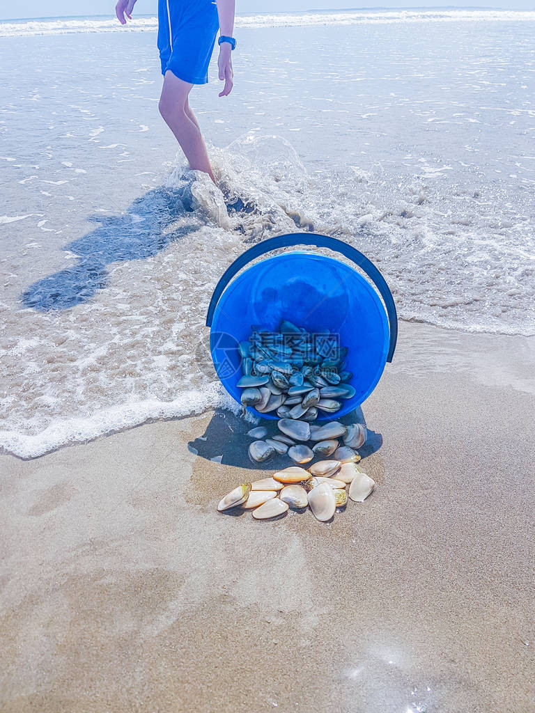 蓝色水桶倒在海滩上洒出收集的Tu图片