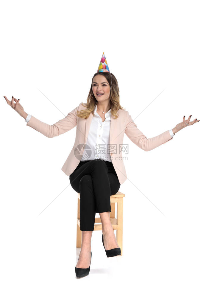戴着生日帽子的快乐女商人在坐木凳子上图片