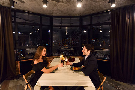 在餐厅约会的浪漫情侣以全景窗背景和夜图片