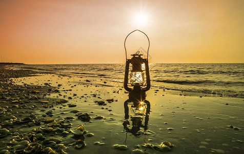 日出时海上的老式油灯背景图片