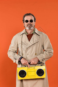 快乐的退休男人拿着黄调音机在橘子上背景图片