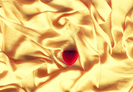 金色丝绸上的红色心形珠宝礼盒图片