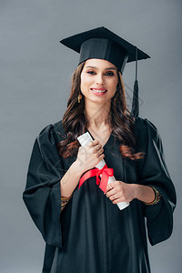 穿着学术礼服和毕业帽子持有文凭孤立在灰色地带的快图片