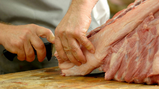 肉店里屠夫手切猪肉的特写屠宰场的新鲜生肉在工图片