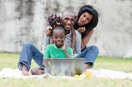 坐在公园的幸福家庭坐在电脑面前在图片