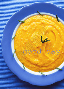 蓝色餐巾上蓝色盘子里的南瓜奶油汤题字美好的一天图片