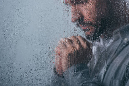 男人用折叠的手在窗口中哭泣用雨背景图片