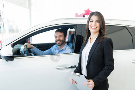 美丽的销售代表在经销商的汽车中为客户提图片