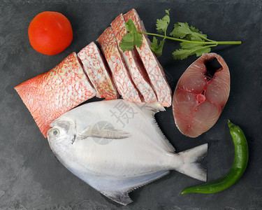 白色鲳鱼西班牙鲭鱼红鲷鱼清洗黑色大理石板背景上的去鳞图片