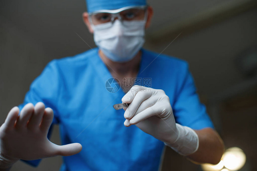 穿着医用特殊衣服戴着防护眼镜戴着手套戴着口罩的塑料医生在手术室里手拿着一把手术刀现代外科图片
