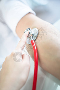 医生用听诊器测量病人的血压图片