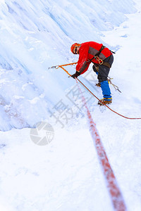 登山者在降雪期间穿越冰川的冰墙图片